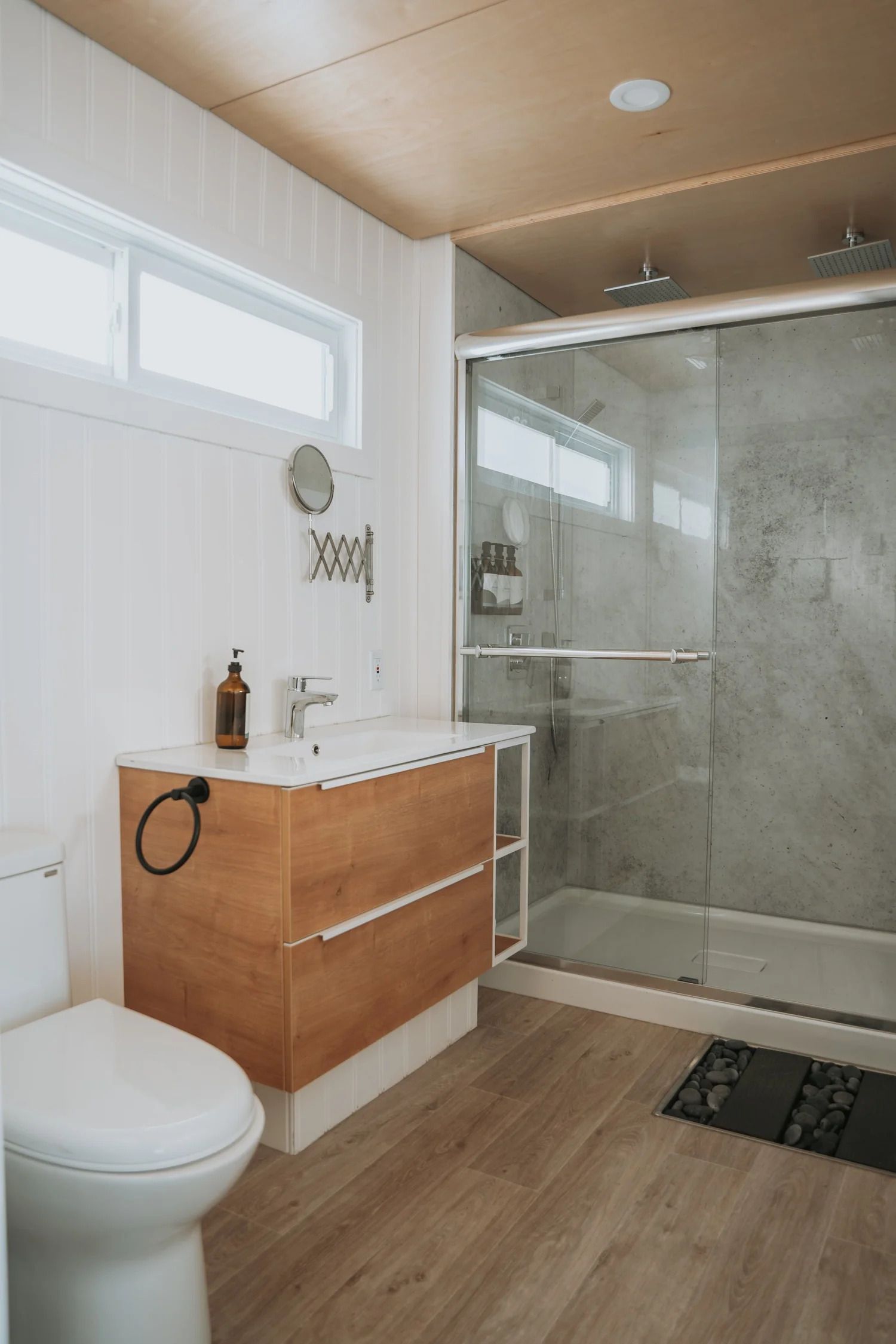 Moderne badkamer met houten wastafelmeubel, toilet en glazen douchecabine.