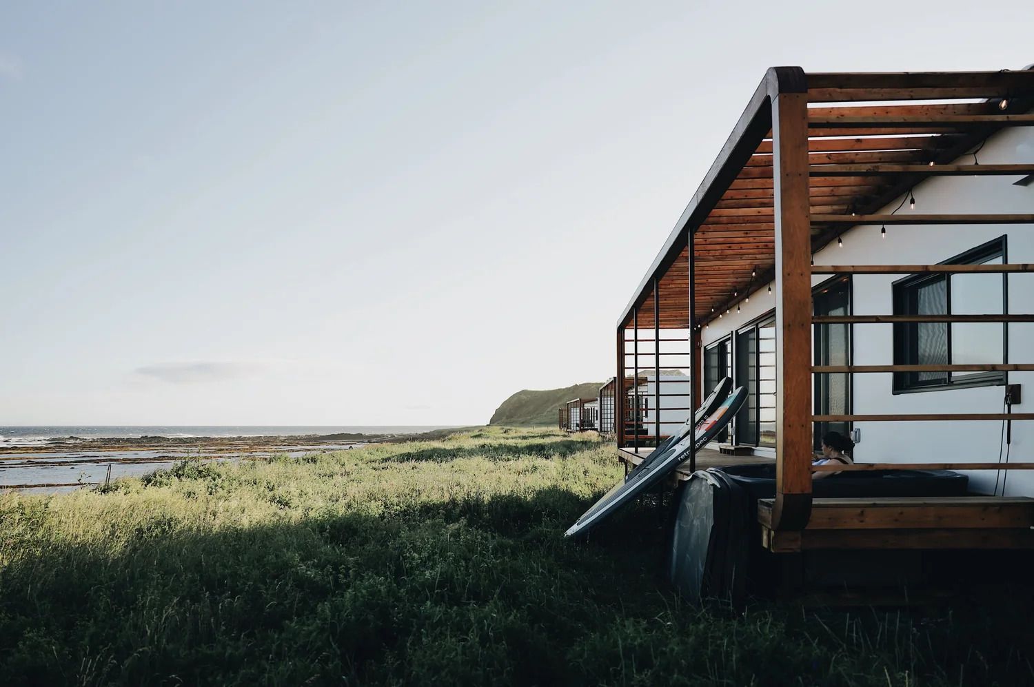 Modern terras bij een huis met uitzicht op een grasrijk moeras en water onder een heldere hemel.