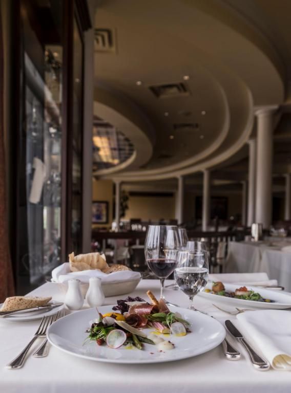 Een elegante restauranttafel met opgemaakte gerechten, wijnglazen en een gebogen plafond op de achtergrond.