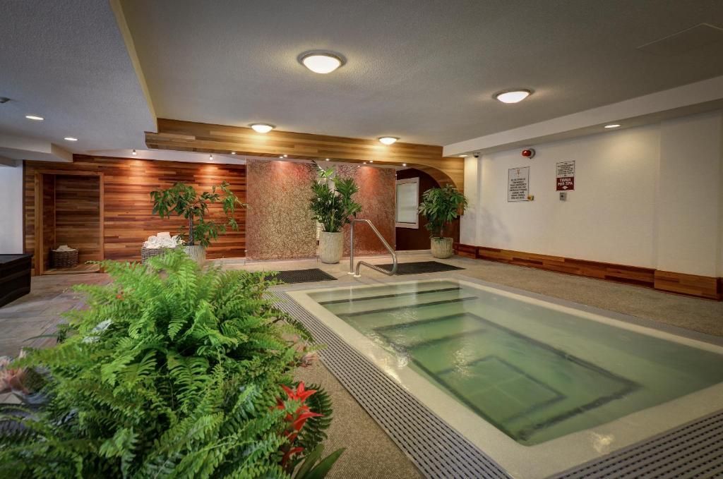 Binnenspa met een kleine jacuzzi, tropische planten en een loungehoek met houten lambrisering.