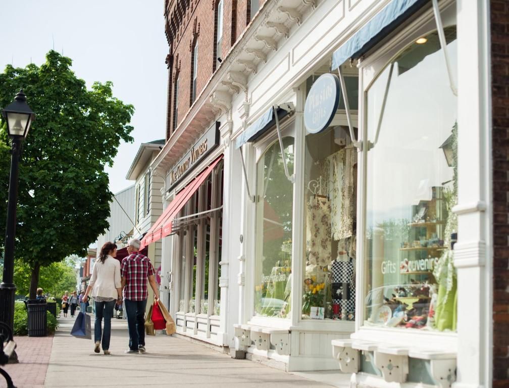Voetgangersstraat met winkels, luifels en mensen die langs etalages lopen.