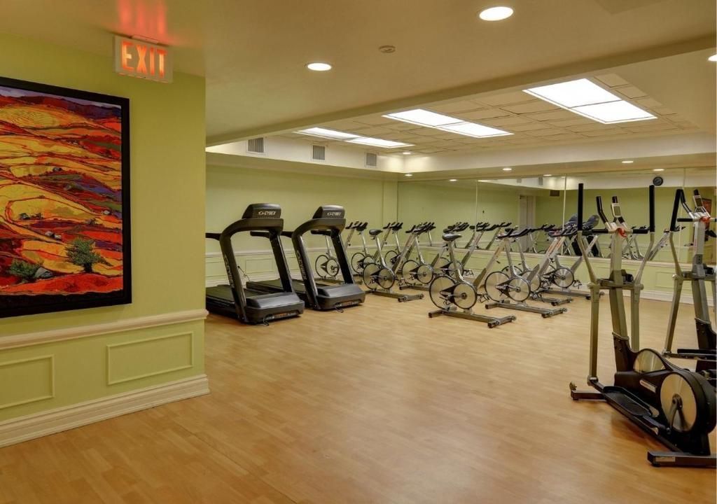 Fitnessruimte met loopbanden, hometrainers en fitnessapparatuur op een houten vloer.
