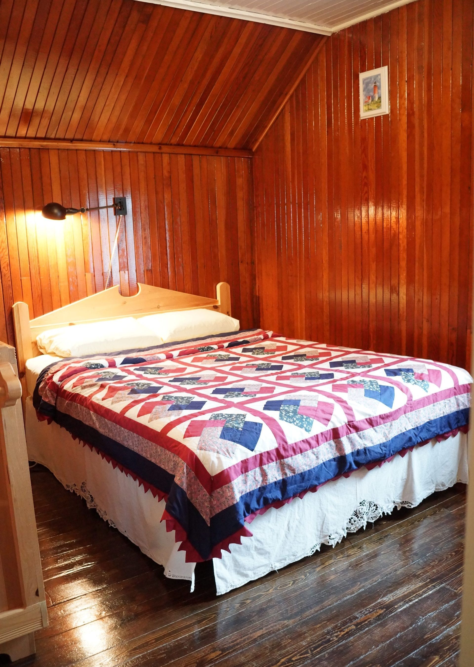 Kleine slaapkamer met houten lambrisering, een netjes opgemaakt bed en een kleurrijke sprei.