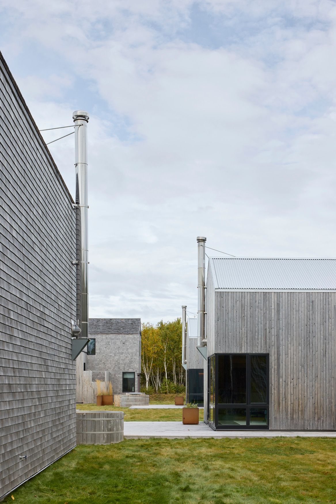 Moderne grijze gebouwen rond een grasveld onder een bewolkte hemel.