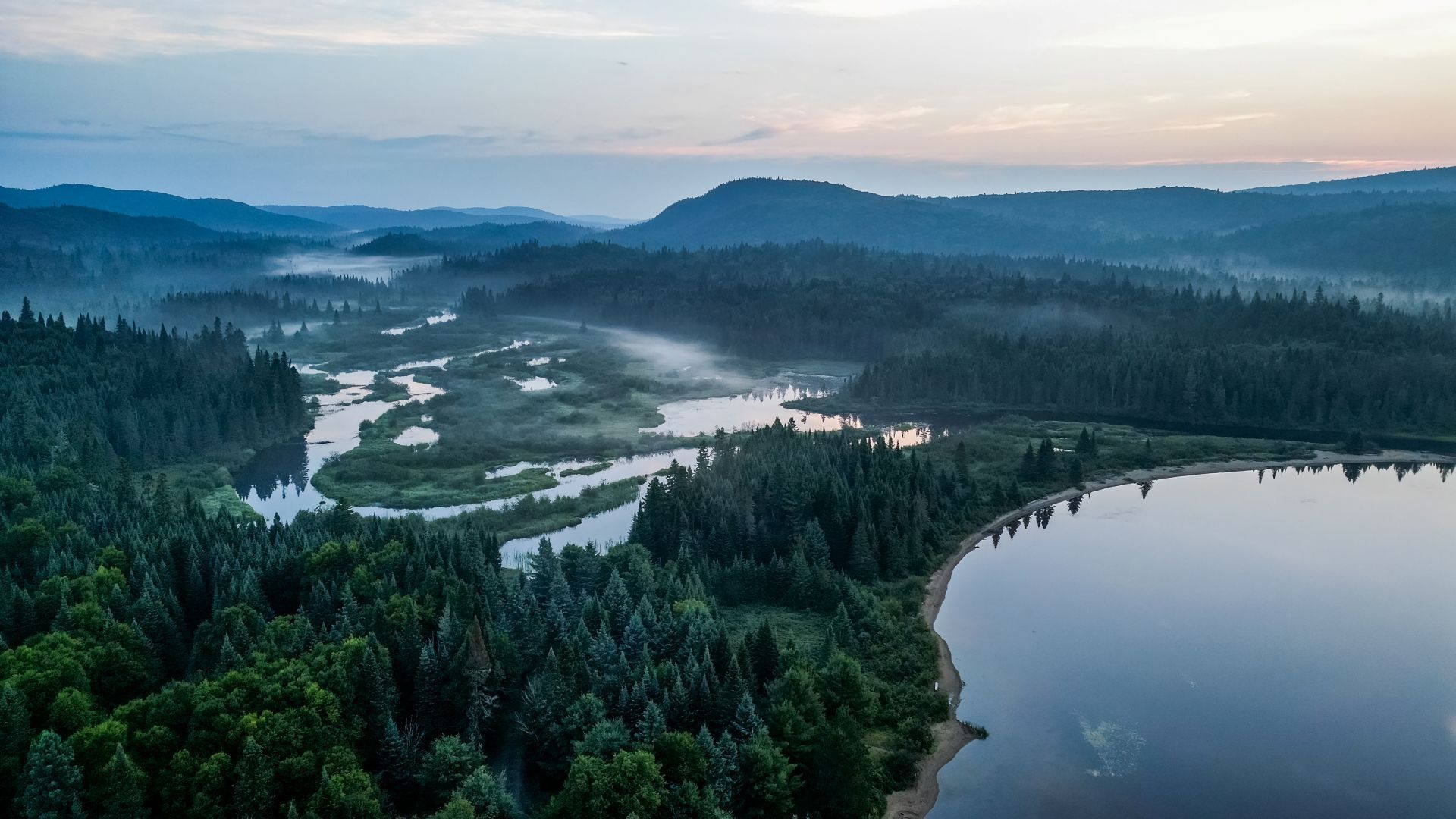 Luchtfoto van het meer Lac Escalier en de rivier Rivière du Diable in het Parc national du Mont-Tremblant Canada in de schemering, met op de achtergrond een rustig meer en heuvels in de verte.