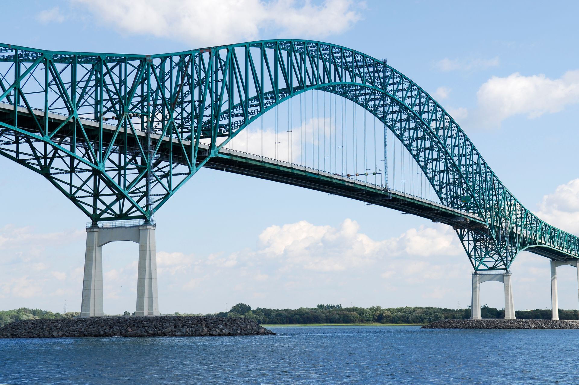 Blauwe stalen boogbrug in in het plaatsje Trois-Rivieres te Quebec, Canada over het St Lawernce rivier onder een gedeeltelijk bewolkte hemel.
