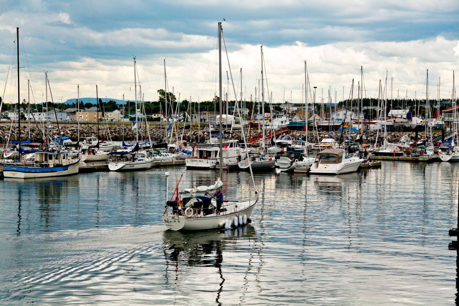 Haven in Rimouski, Quebec Canada, met veel zeilboten en jachten aangemeerd op kalm water onder een bewolkte hemel.
