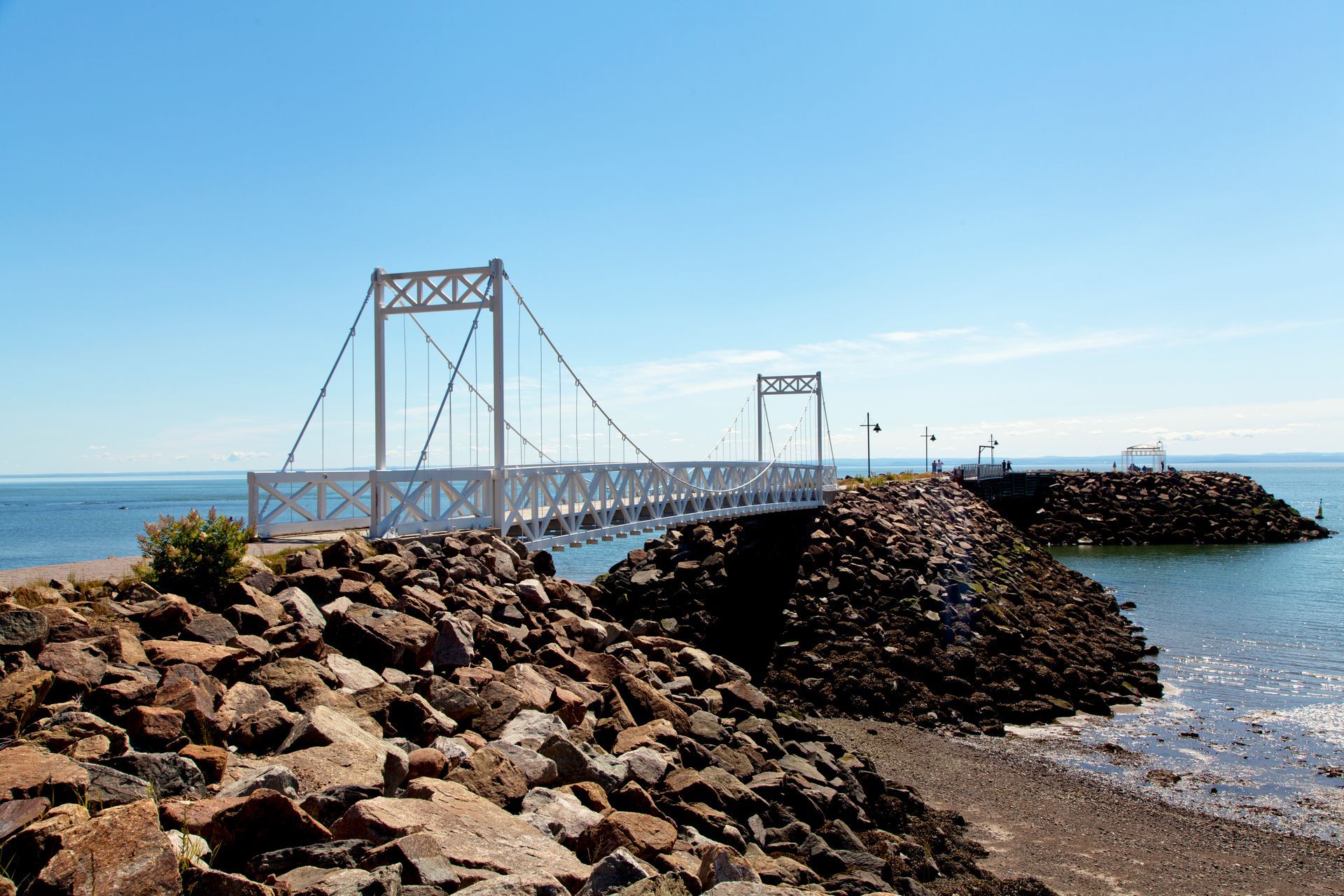 Witte hangbrug op de rotsachtige pier van La Malbaie in Quebec, Canada, onder een heldere hemel.