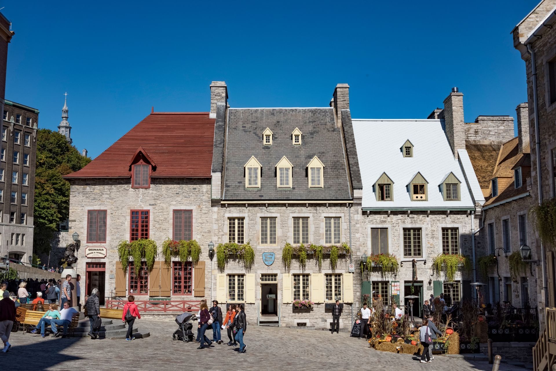 Historisch stadsplein Place Royale in Old Quebec met kleurrijke gevelgebouwen en mensen die zich op een zonnige dag hebben verzameld.