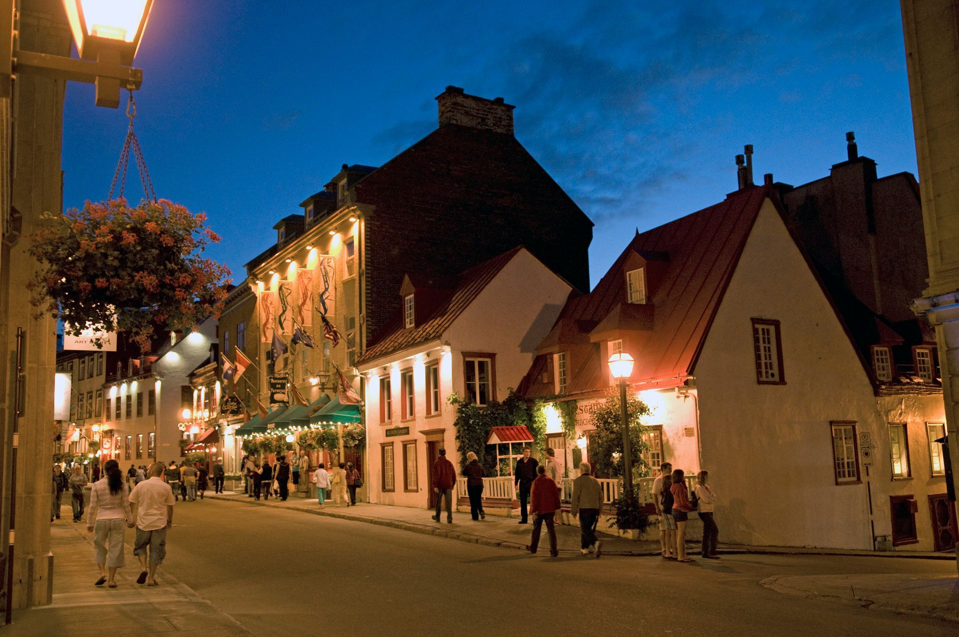 De avondstraat Rue Saint-Louis in Quebec met verlichte winkelpanden, voetgangers en warme lantaarnpalen.