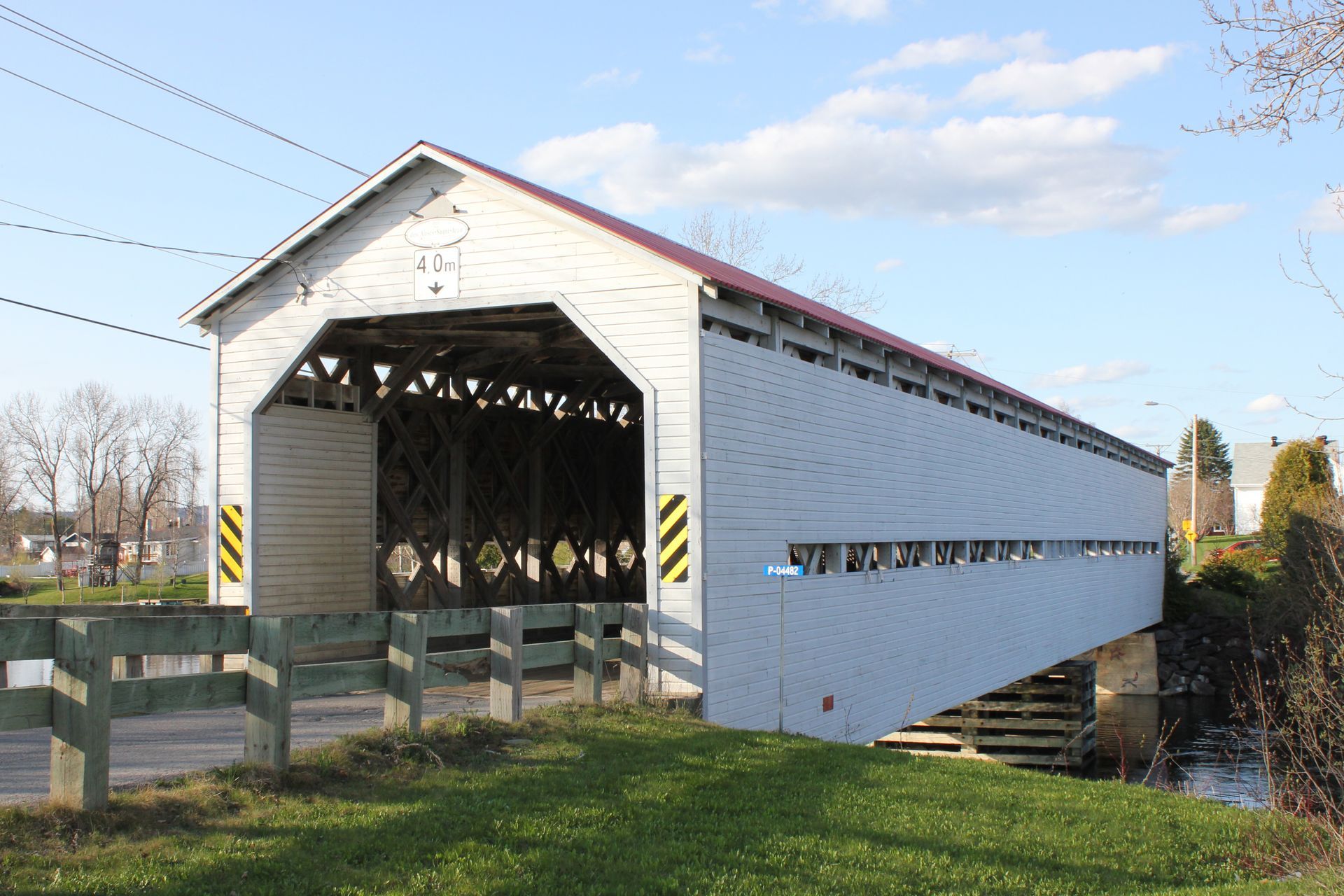 Covered Bridge in Amqui, Quebec Canada, met witte zijwanden, gezien vanaf de buitenkant op een zonnige dag.