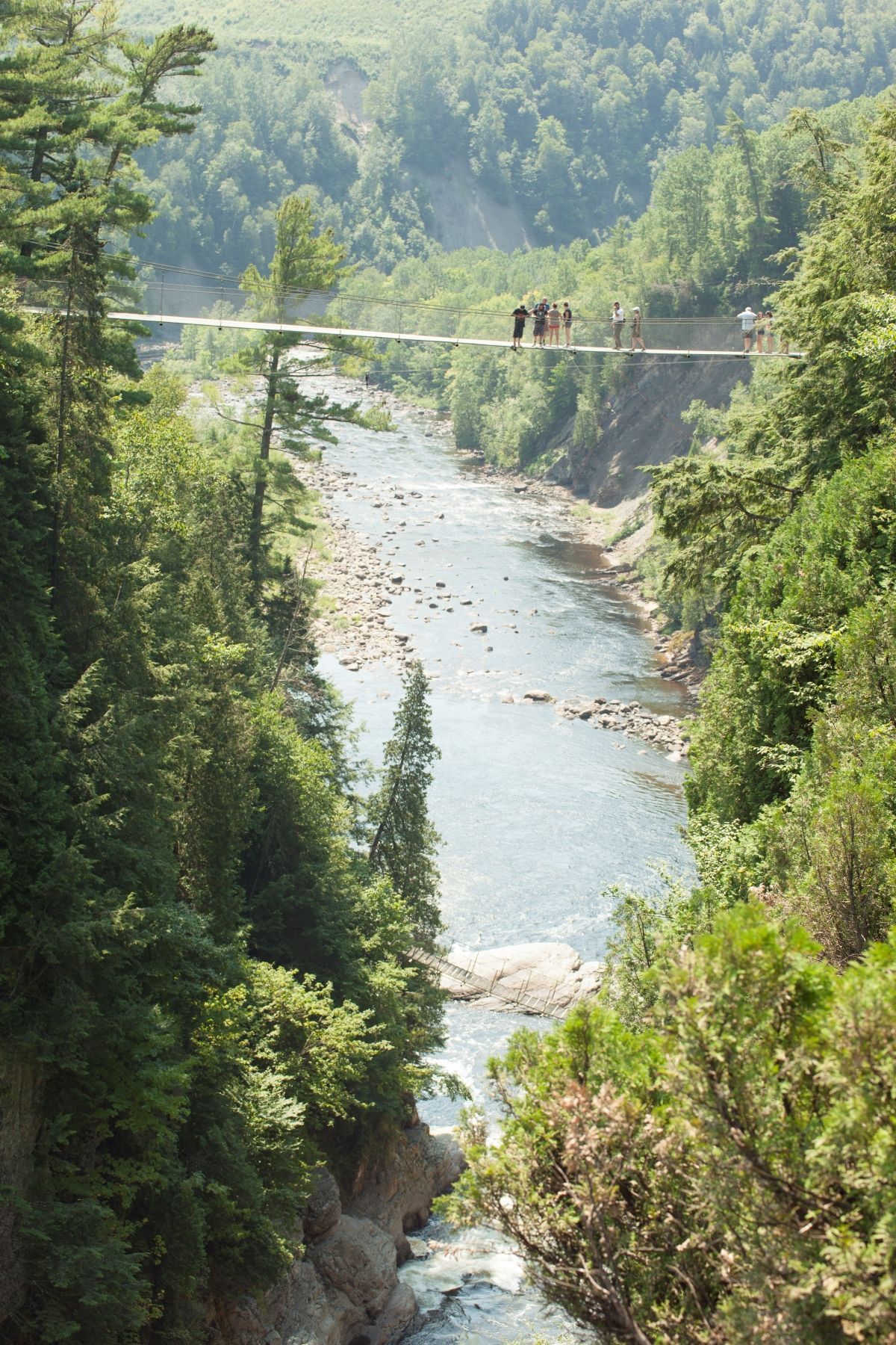 Hangbrug over de beboste rivierkloof Canyon Sainte-Anne in Canada met twee mensen erop.