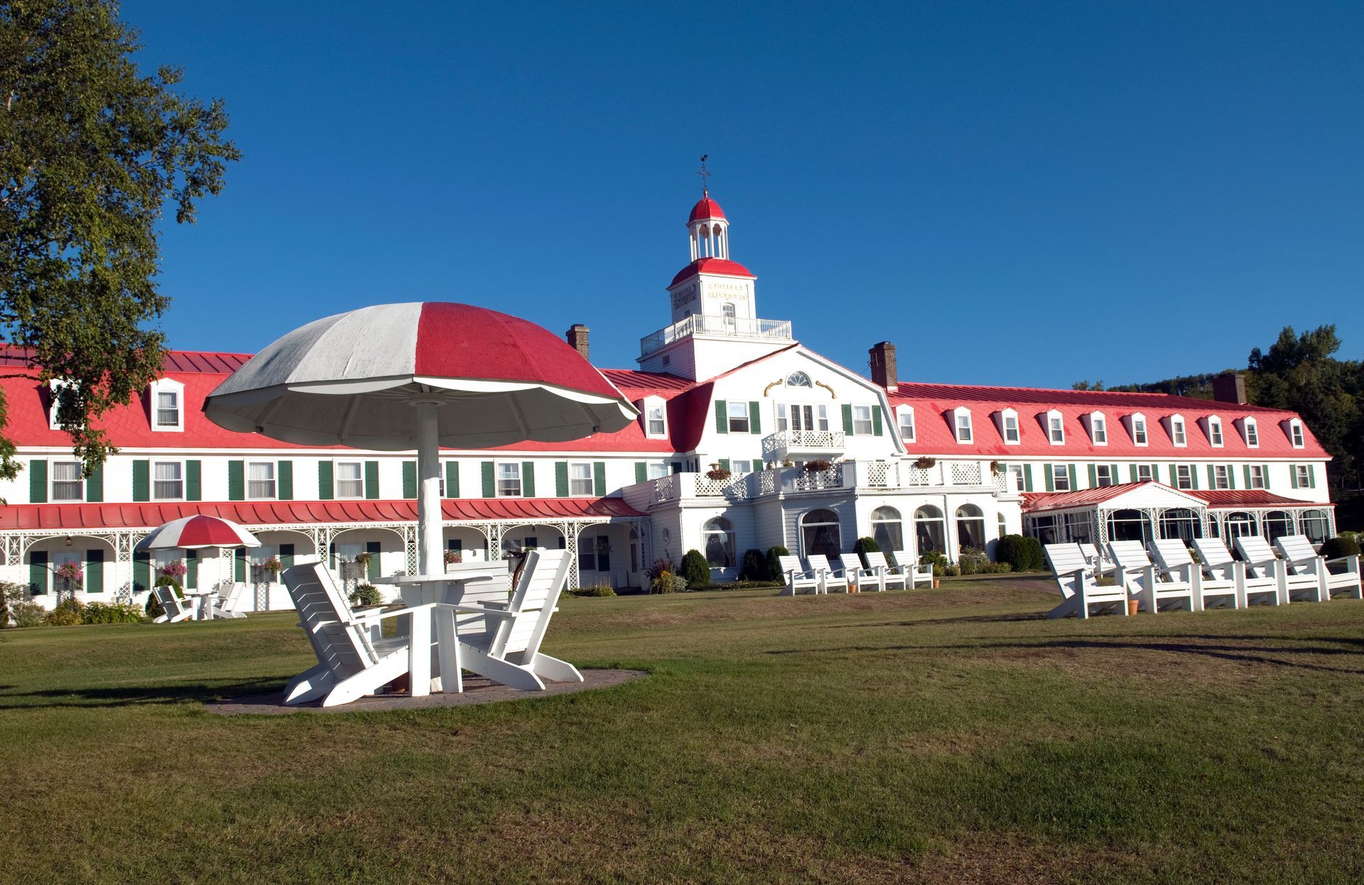 Hotel Tadoussac in Canada met rode daken, ligstoelen en een blauwe hemel.