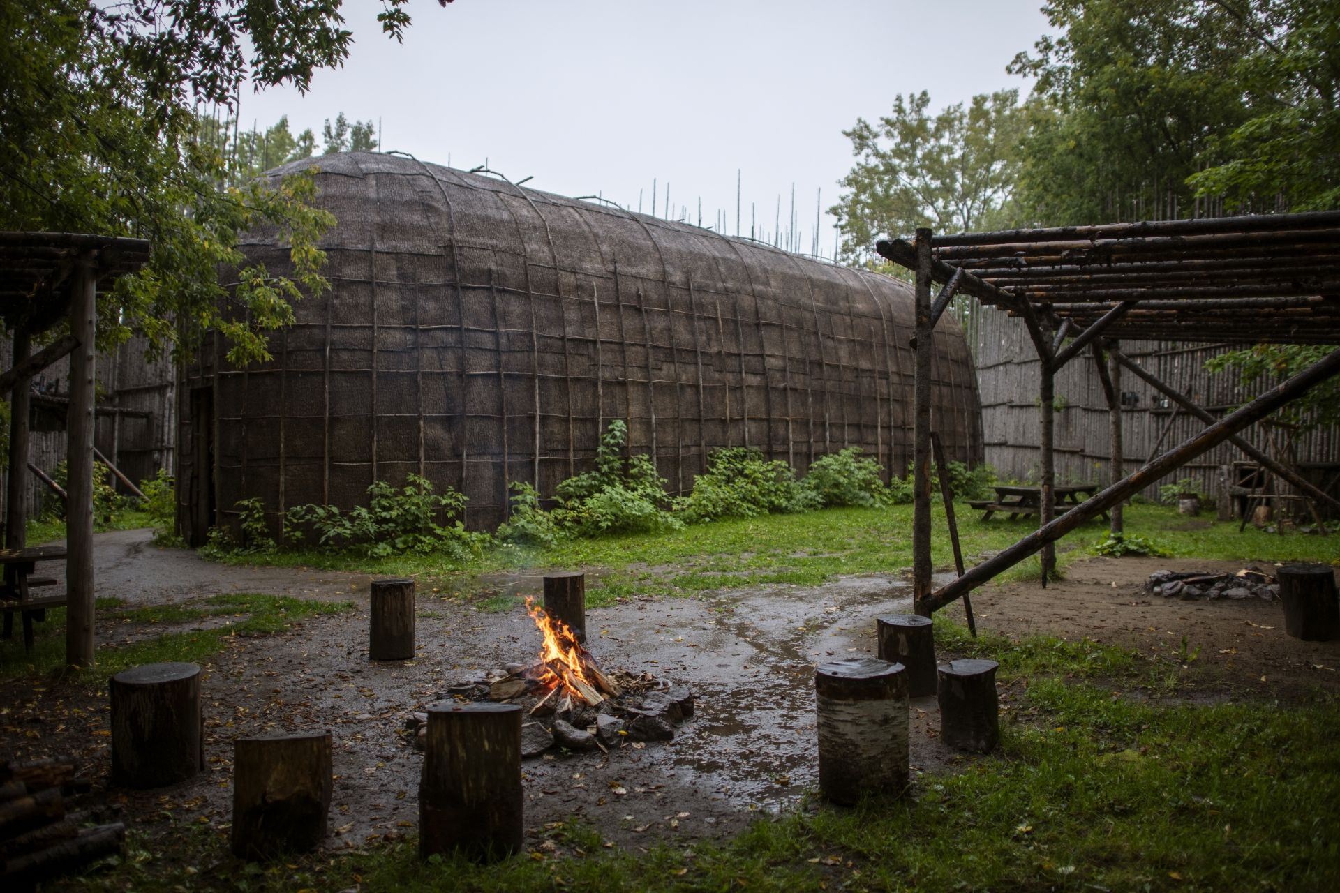 Een klein kampvuur op een modderige open plek naast de traditionele Longhouse in Huron Traditional Site ONHOÜA CHETEK8E in Canada.