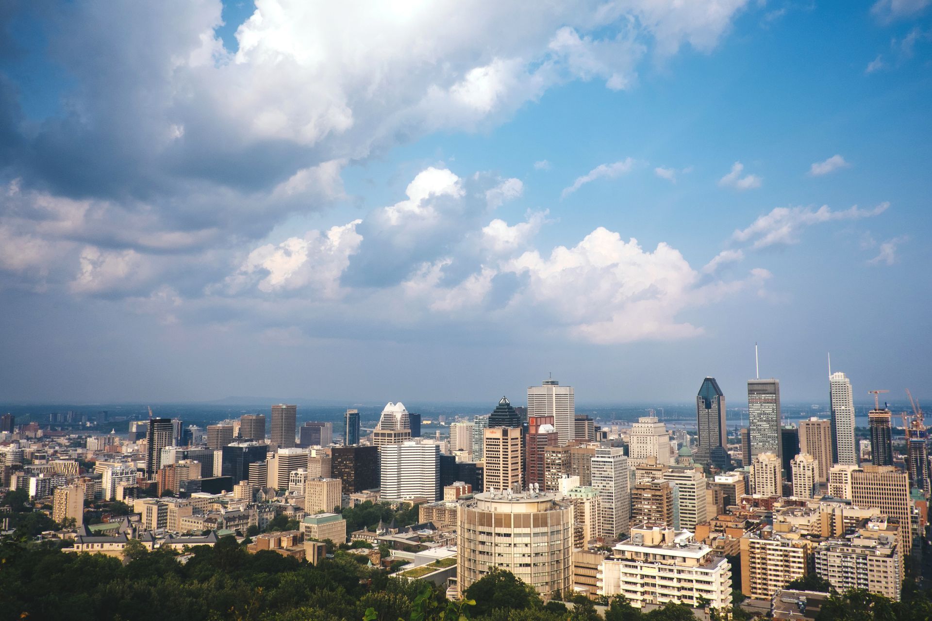 Stadsgezicht op Montreal met hoge gebouwen onder een helderblauwe hemel en verspreide wolken.