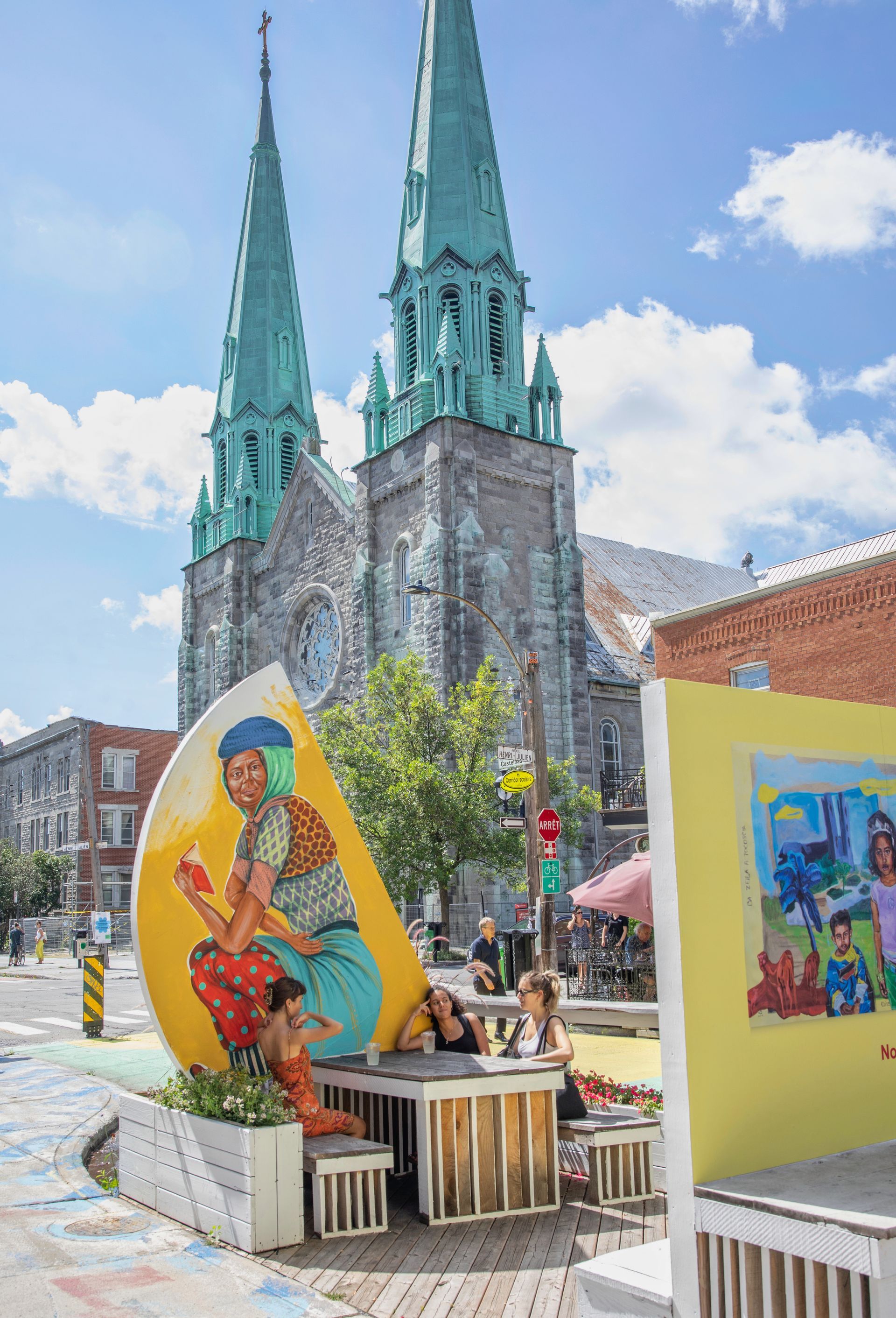 Een terras in Montreal, Canada, met kleurrijke muurschilderingen voor twee groene kerktorens.