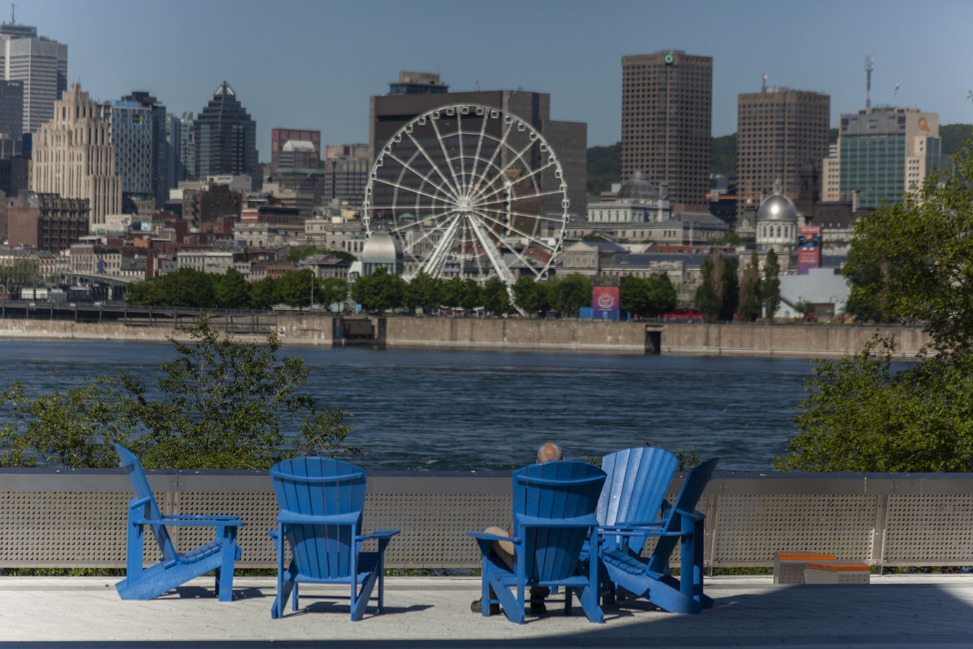 In blauwe Adirondack-stoelen staat een prachtig uitzicht op de waterkant met een reuzenrad en de skyline van Montreal op de achtergrond.