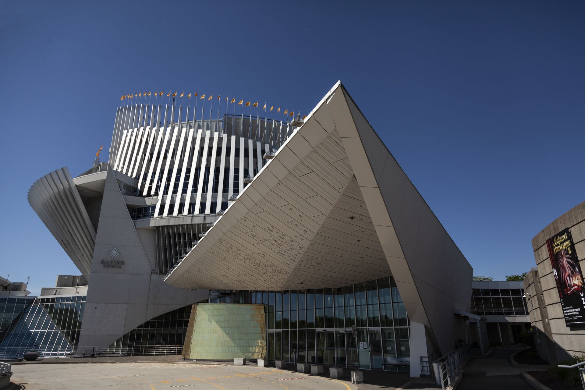 Het casino van Montreal met glazen gevel en witte geometrische panelen onder een helderblauwe hemel.