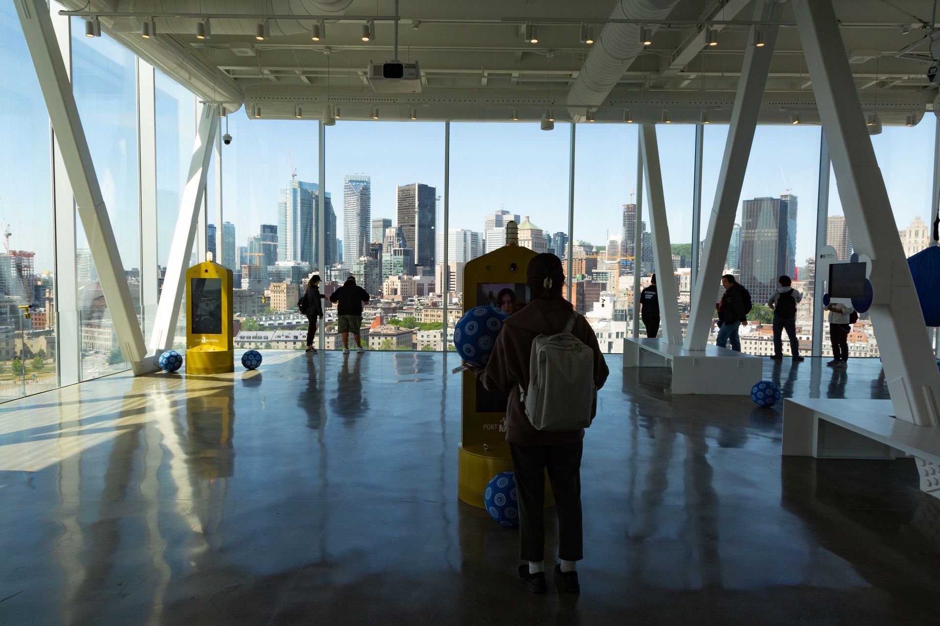 Mensen lopen door een lichte, glazen terminal met uitzicht op de skyline van de stad Montreal.