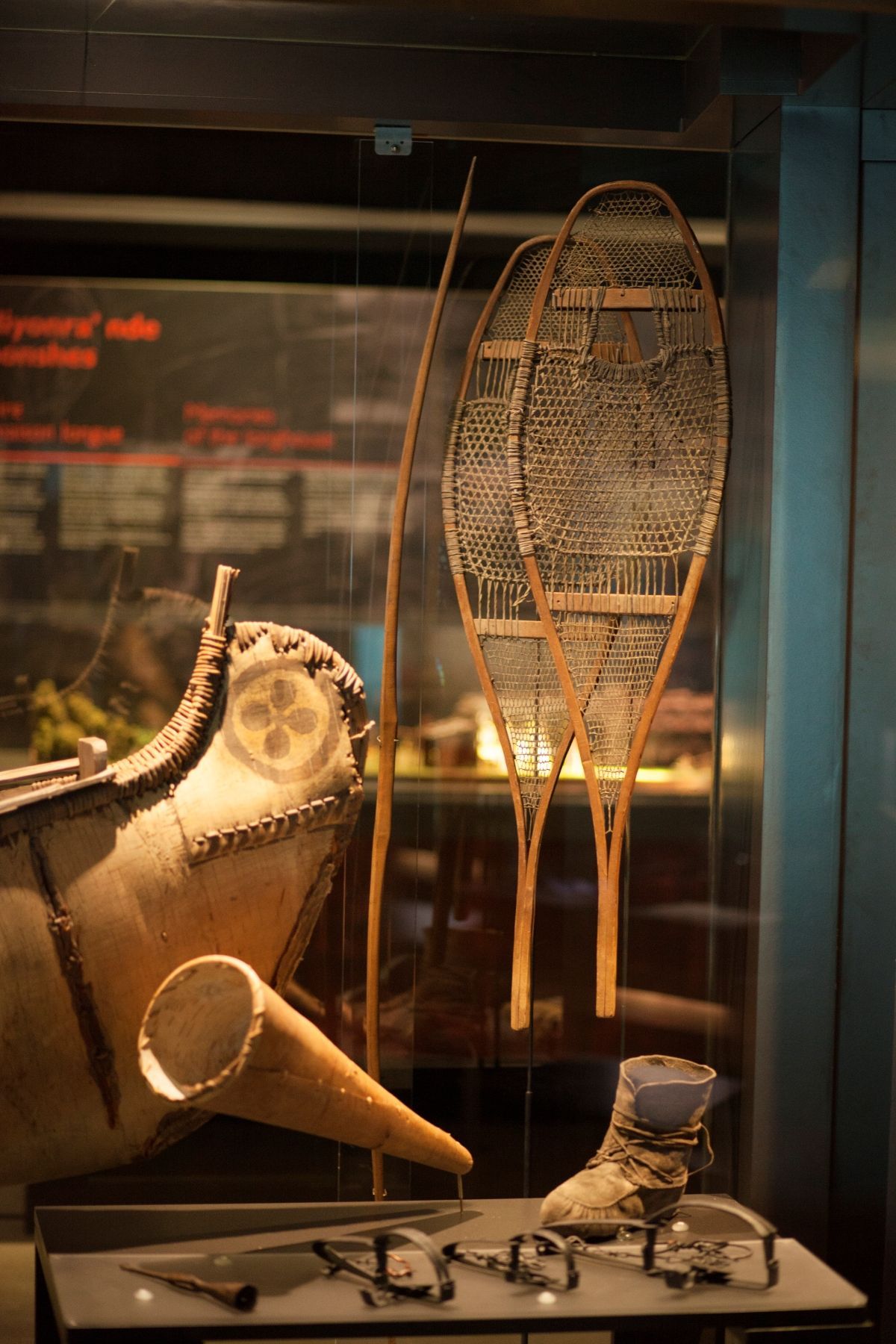 Een kano, een kegel, oude schaatsen en sneeuwschoenen van First Nations tentoongesteld in een museumvitrine van Musée Premières Nations in Canada