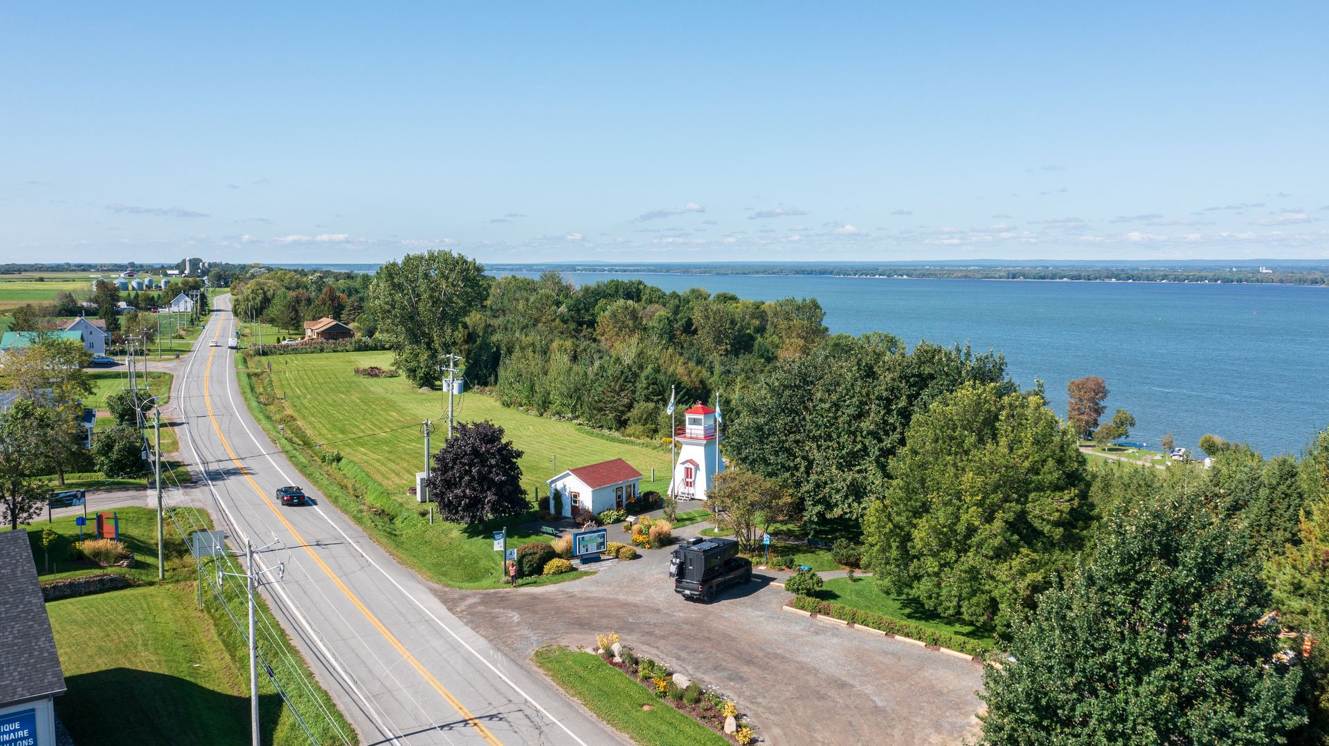 De kustweg langs de St. Lawrence River in Canada met groene bomen en onder een heldere hemel.