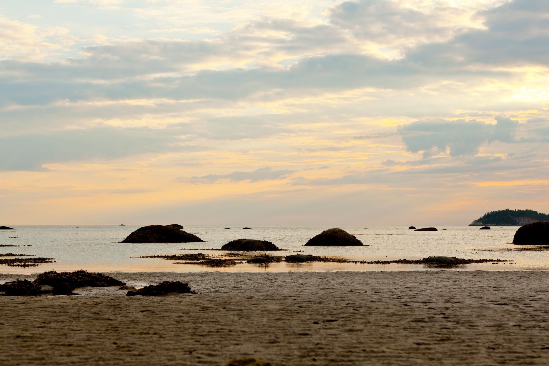 Rotsachtig strand in Parc national du Bic in Quebec, Canada, bij zonsondergang met kalm water en pastelkleurige wolken.