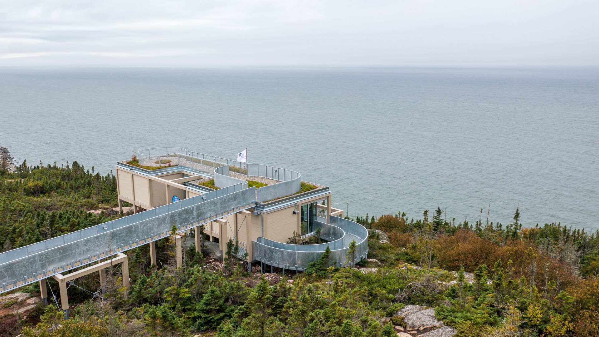 Putep ’t-awt Cacouna observation site in Quebec, Canada, met gebogen metalen loopbruggen die uitzicht bieden op de zee en de bewolkte horizon.