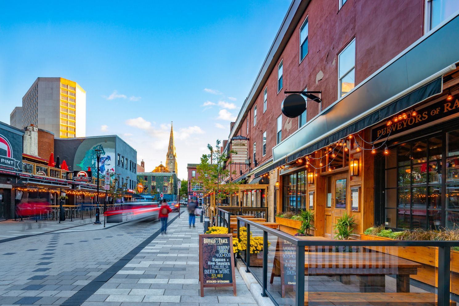 Argyle Street in Halifax op Nova Scotia, Canada, met terrasjes, bakstenen gebouwen en een klokkentoren in de verte bij zonsondergang.