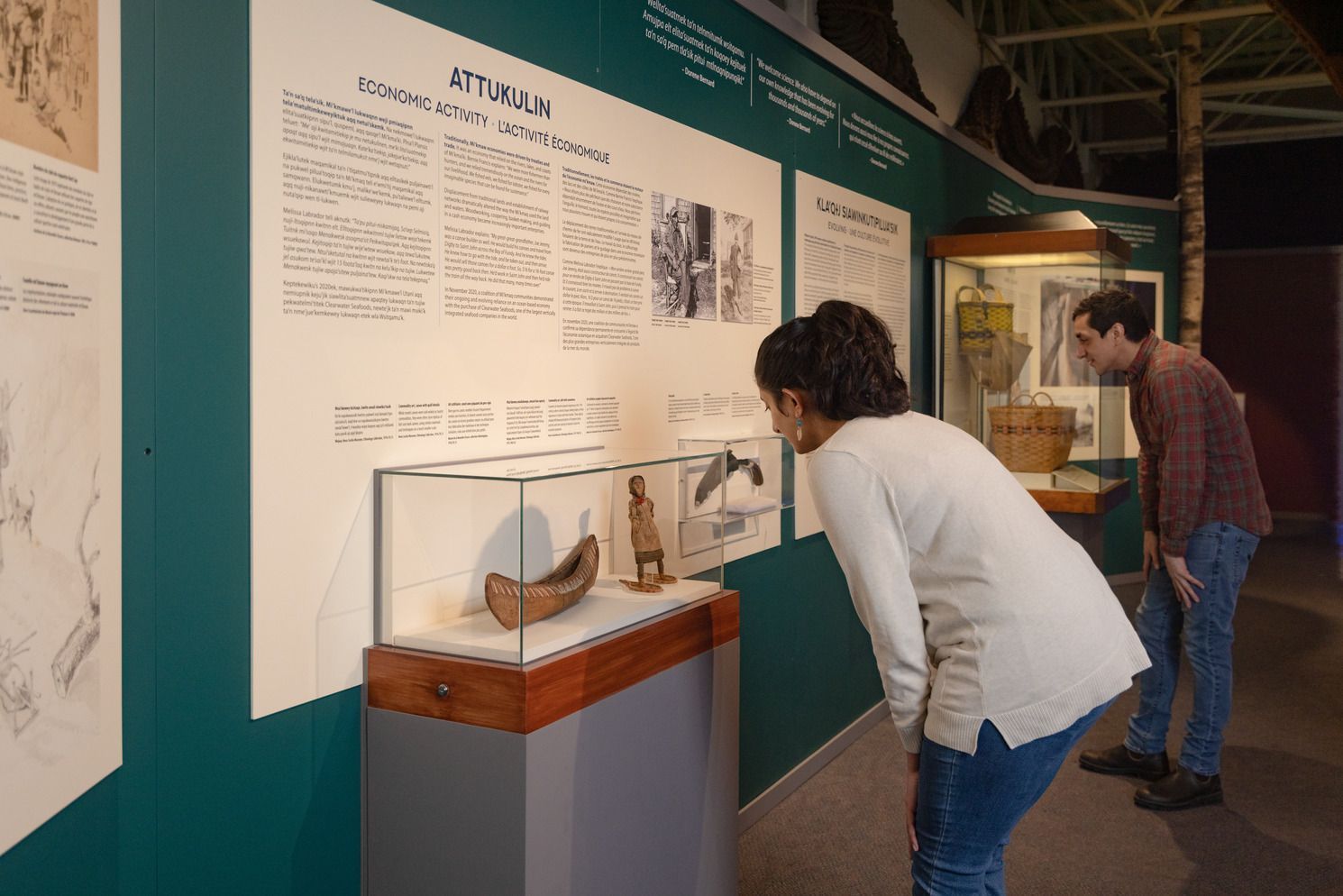 Museumexpositie in het Maritime Museum of the Atlantic in Halifax met twee bezoekers die wandteksten lezen naast een glazen vitrine.