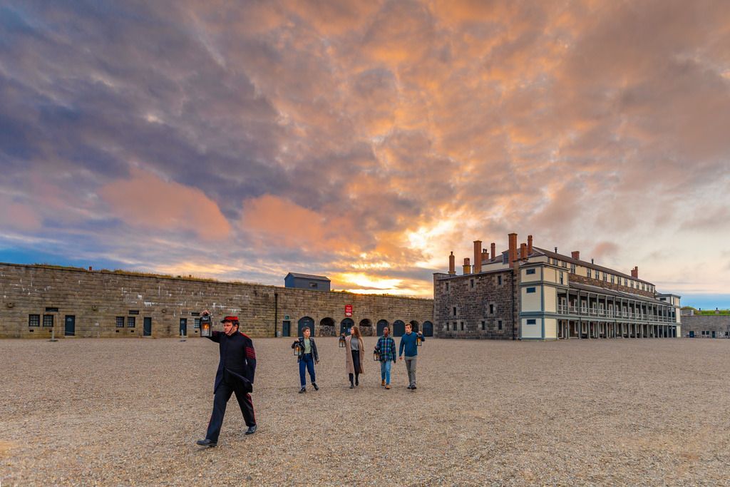 Mensen lopen over de binnenplaats van de citadel van Halifax op Nova Scotia in Canada bij een stenen gebouw bij zonsondergang onder een dramatische bewolkte hemel.