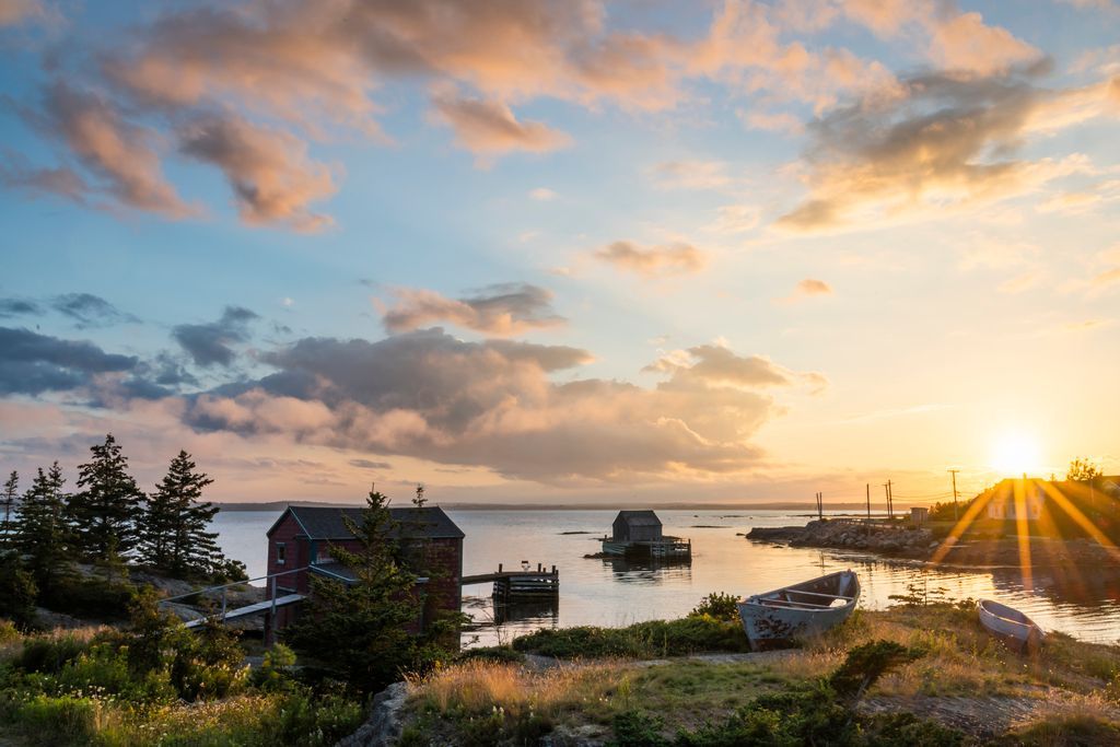 Zonsondergang boven de rotsachtige haven van Blue Rocks op Nova Scotia met boten, kalm water en roze wolken.