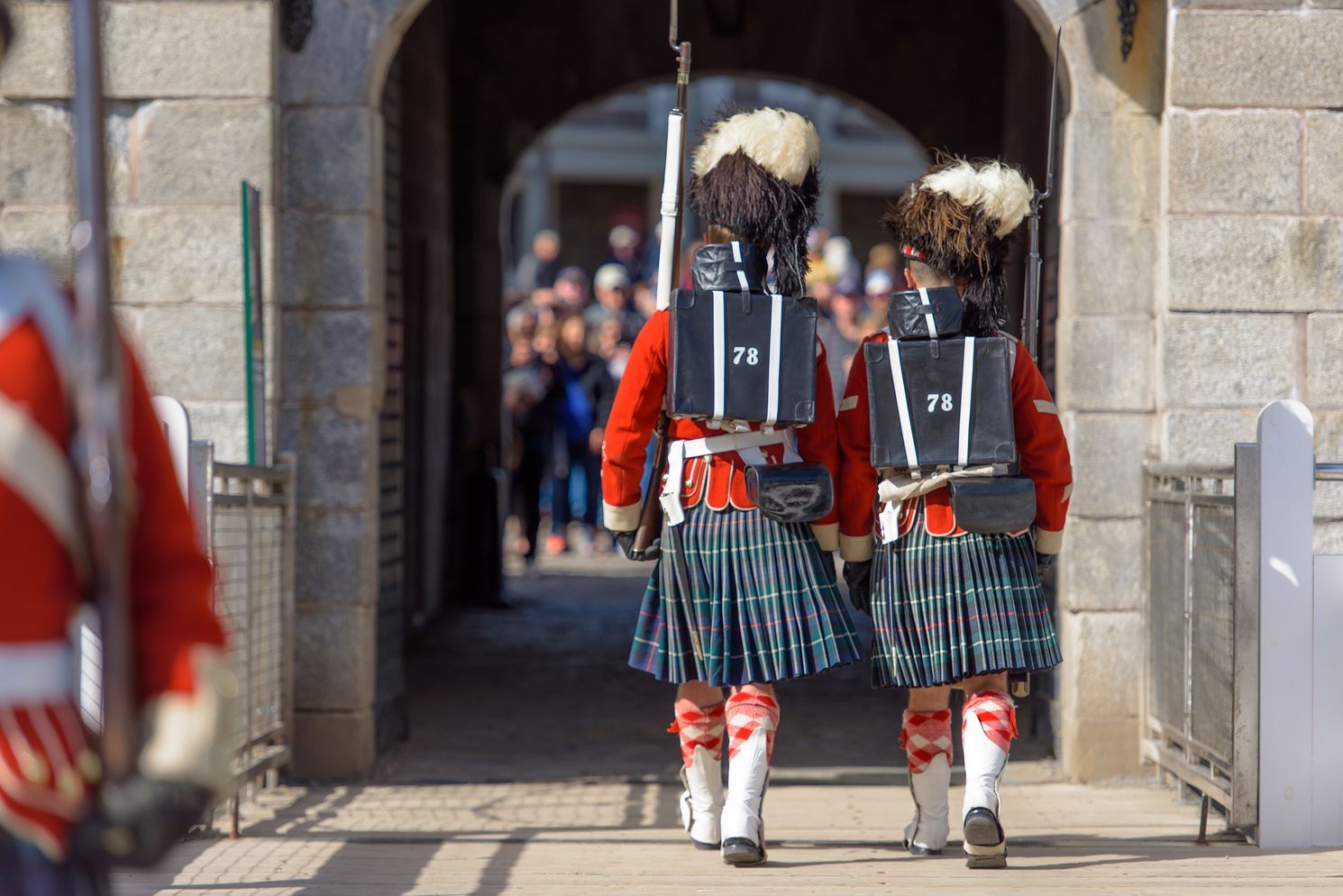 Twee mensen in traditionele Schotse klederdracht lopen door een stenen boog tijdens een ceremonie in de citadel van Halifax op Nova Scotia in Canada.