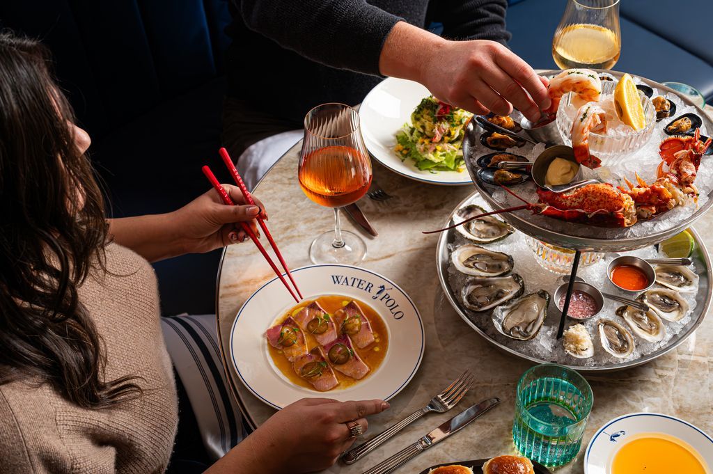 Mensen die aan een tafel zitten te dineren in Halifax op Nova Scotia in Canada met zeevruchten, kommen, drankjes en eetstokjes, gezien van bovenaf.