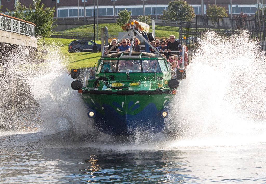 Een groen amfibisch voertuig van Hopper Boat Tours scheurt door het water en veroorzaakt grote spetters in een rivierkanaal in Halifax op Nova Scotia in Canada.