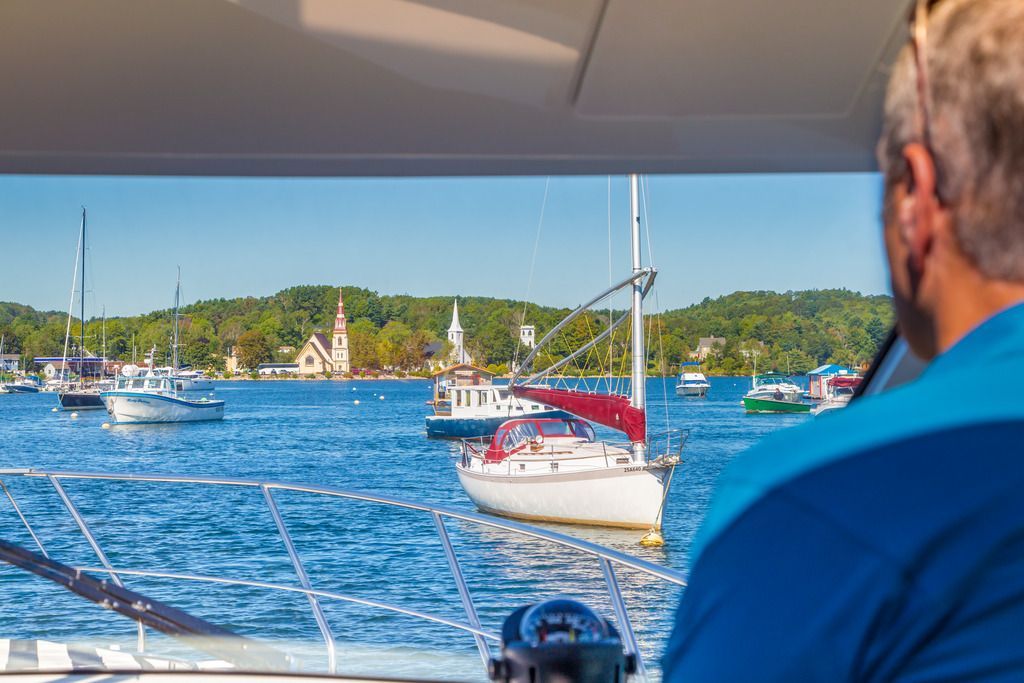 Uitzicht vanaf een boot op zeilboten op blauw water nabij de beboste kustlijn van Mahone Bay op Nova Scotia.