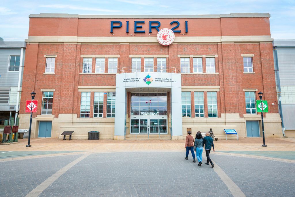 Ingang van Canadian Museum of Immigration op Pier 21 in Halifax op Nova Scotia in Canada met drie mensen die ervoor lopen.