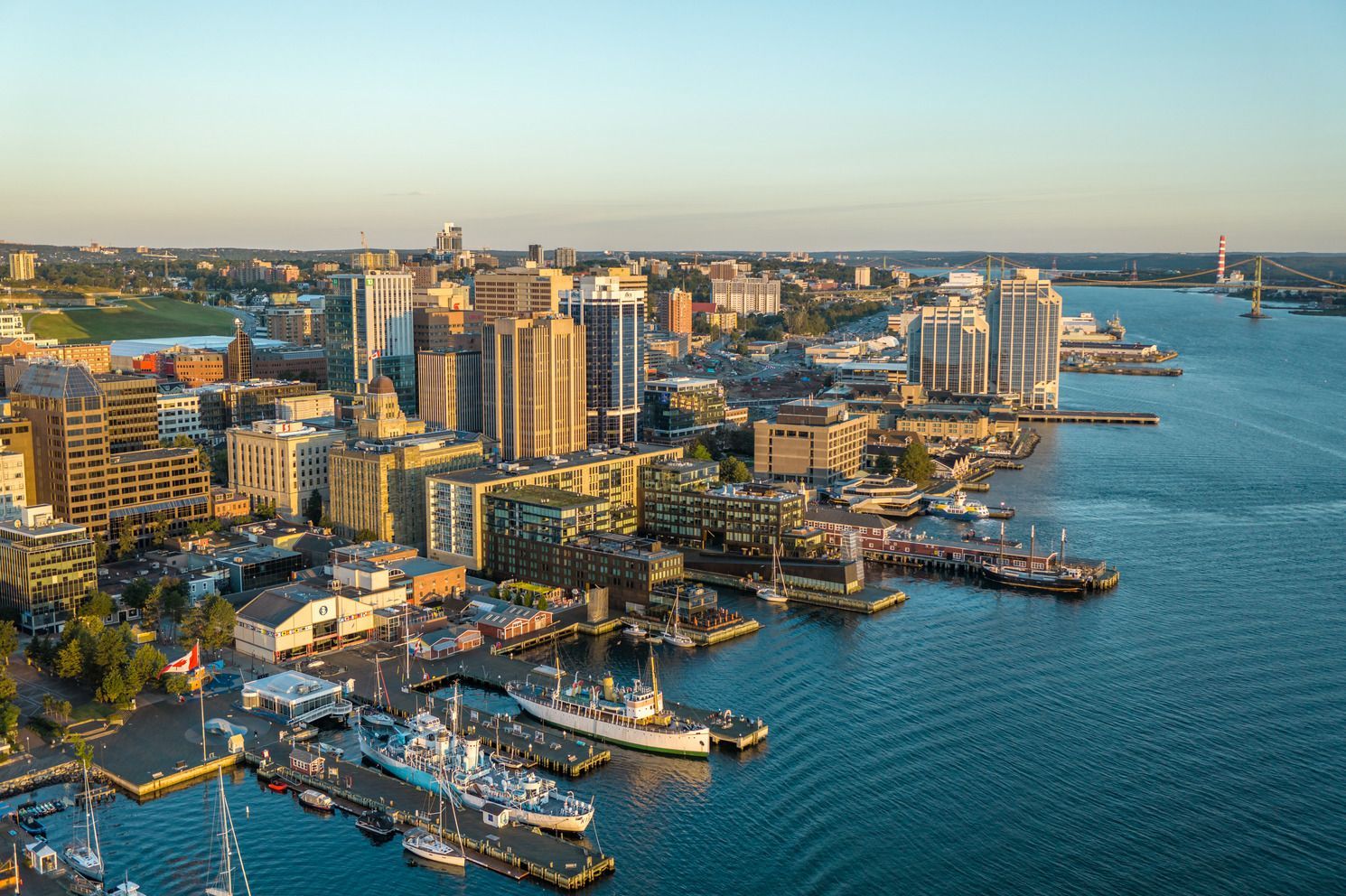 Luchtfoto van de skyline van Halifax op Nova Scotia, Canada, en een jachthaven bij zonsondergang, met boten die langs de waterkant aangemeerd liggen.