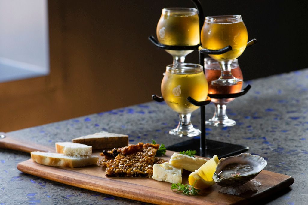 Diverse hapjes op een houten plank met gele drankjes in wijnglazen op tafel in  Halifax op Nova Scotia, Canada.