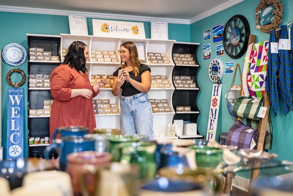 Twee mensen in gesprek in de kleurrijke winkel van Seaweed Soap Company in Chester op Nova Scotia met schappen vol huidverzorgingsproducten.