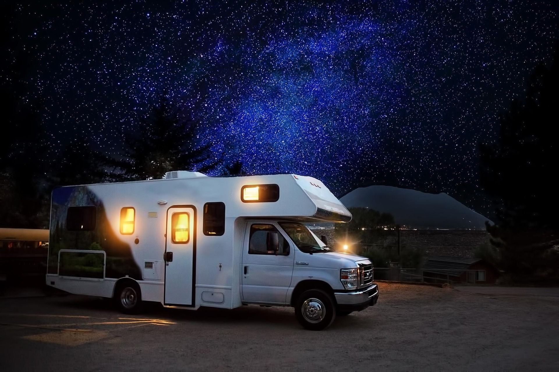 White RV parked outdoors under a dark night sky filled with stars.