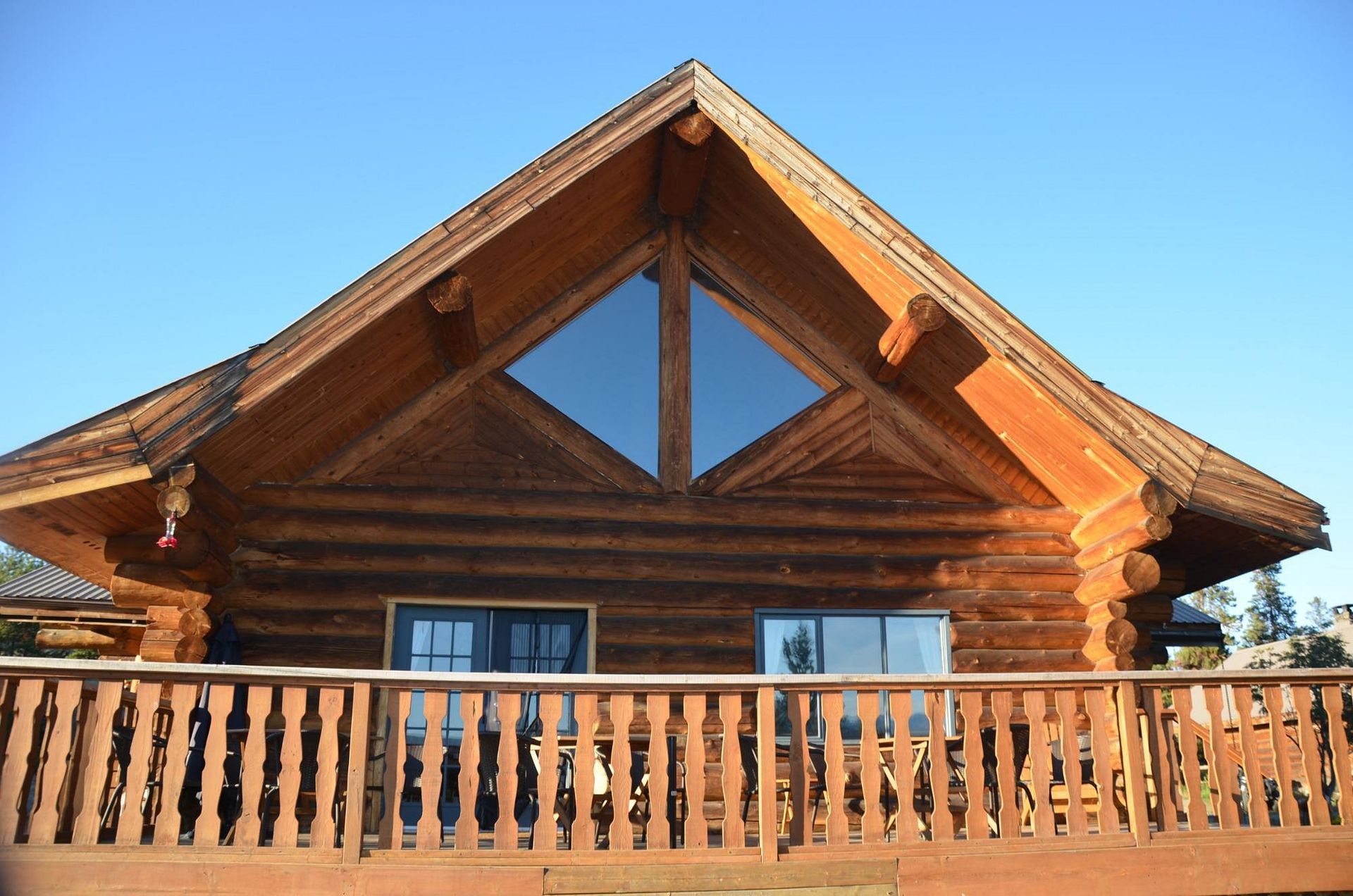 Houten hut met een steil zadeldak en een balkon aan de voorzijde onder een helderblauwe hemel.