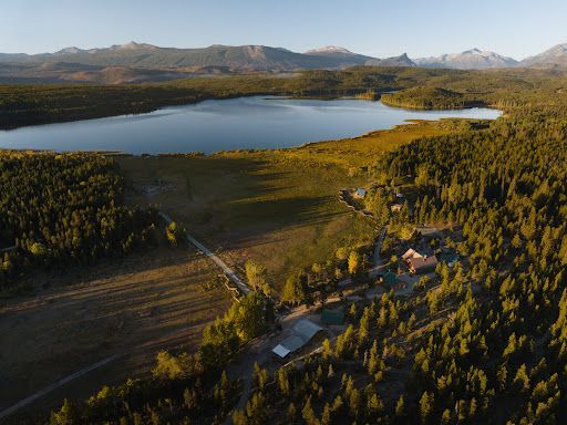 Luchtfoto van Terra Nostra Guest Range meerbekken met bergen en een kleine hut bij zonsondergang.