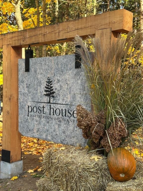 Post House-bord op een houten frame met herfstdecoratie, hooibalen, grassen en een pompoen.