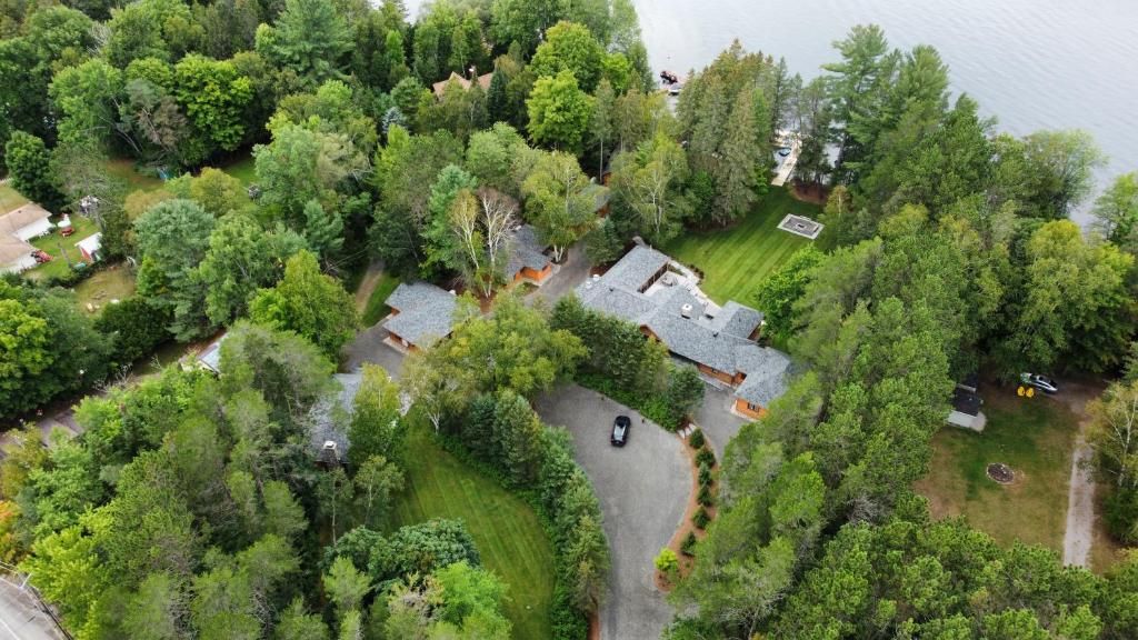 Luchtfoto van een huis met een grijs dak, omgeven door dichte groene bomen en een gebogen oprit.