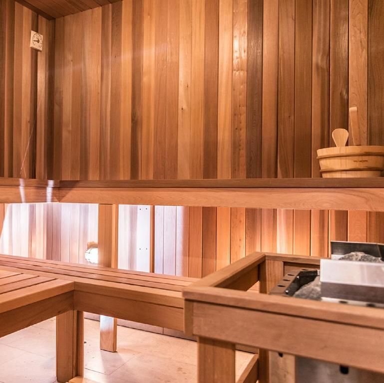 Sauna met houten lambrisering, banken, emmer en pollepel erin.