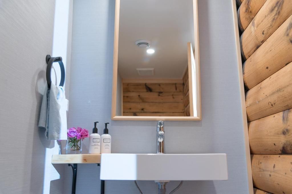 Minimalistische badkamer met wastafel, spiegel, kaars, handdoek, bloemen en houten lambrisering.