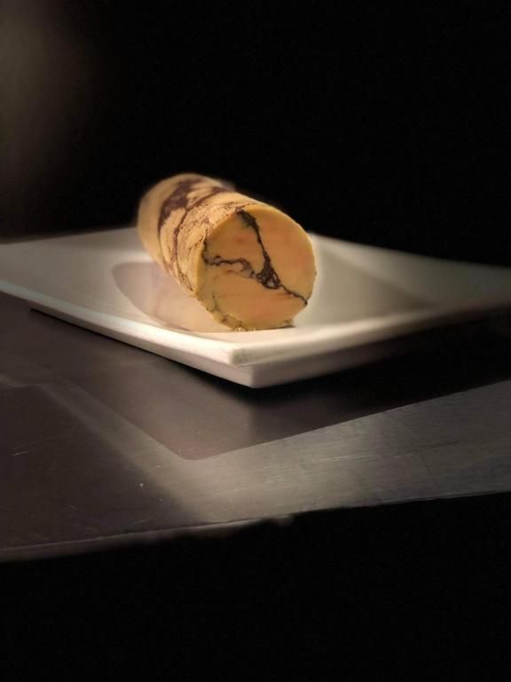 Een doorgesneden dessertrol op een wit bord tegen een donkere tafel en achtergrond.