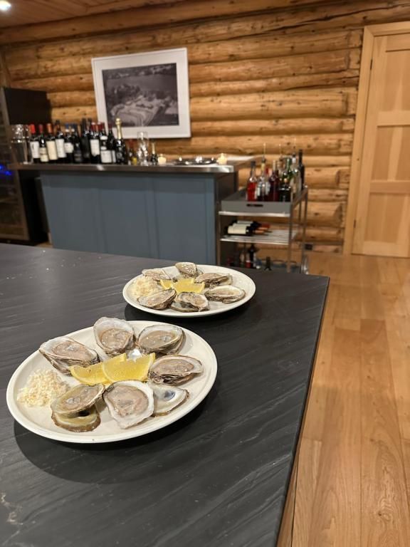 Oesters op borden op een bar in een rustieke, met houten lambrisering beklede ruimte.