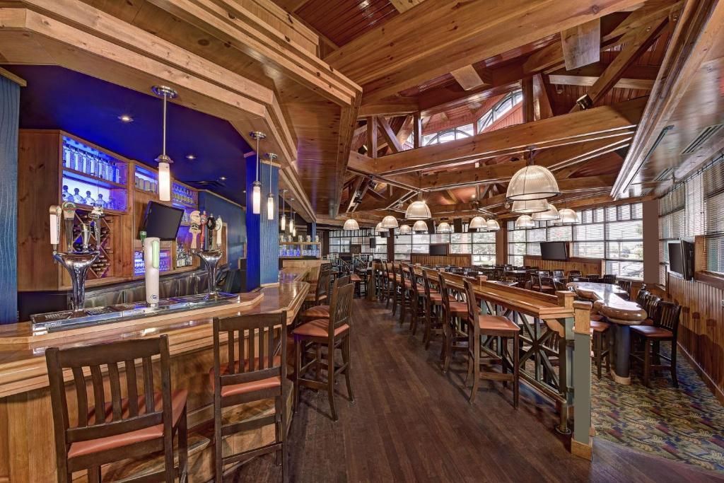 Rustiek restaurantinterieur met houten balken, barkrukken en warme sfeerverlichting.