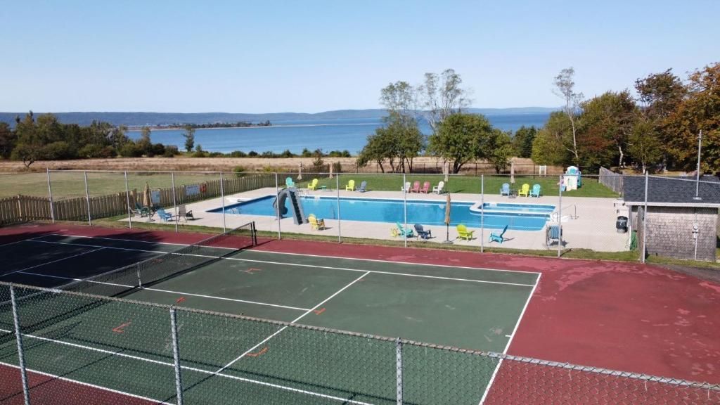 Tennis- en zwemcomplex in de openlucht met banen op de voorgrond en een meer op de achtergrond.
